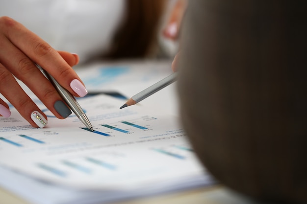 Female arm holding silver pen with financial graph