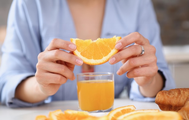 Foto le braccia femminili tengono diapositive d'arancia e un bicchiere di succo