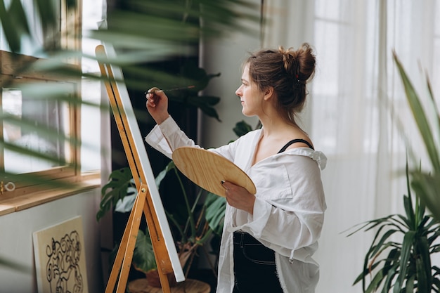 Female artist drawing with brush on canvas