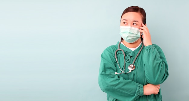 female asia surgeon,surgeon Feeling anxious, showing stethoscope wearing protective mask infectious diseas and coronavirus or covid-19,   in studio With copy space.