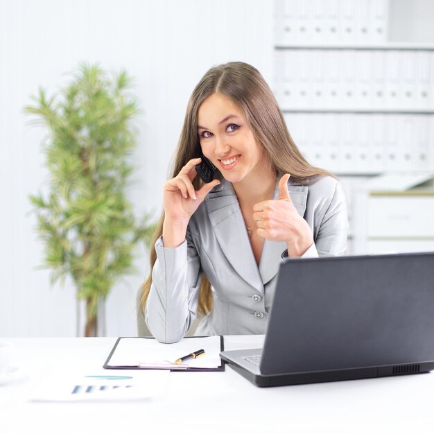 Assistente femminile che parla al telefono seduto dietro una scrivania