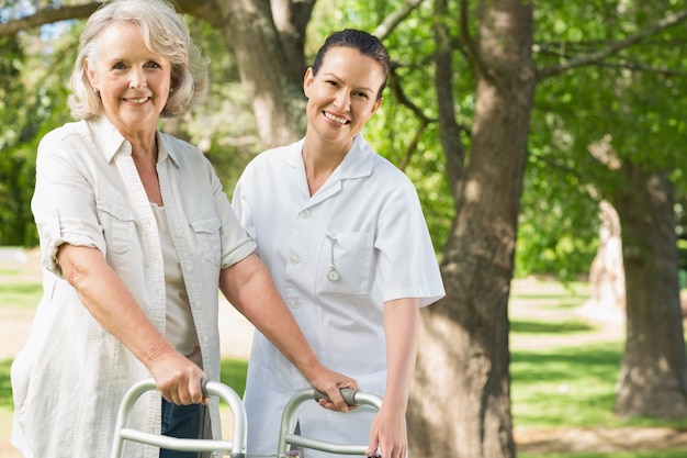 Female assisting mature woman with walker at park