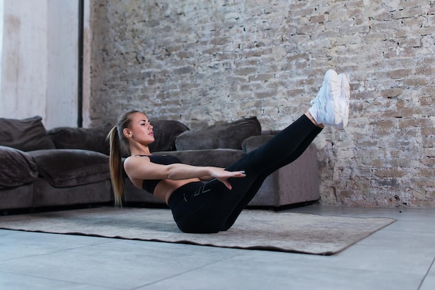 静的腹筋vを行う女性アスリートは、ロフトスタジオの床でコア筋肉を強化する運動を保持します