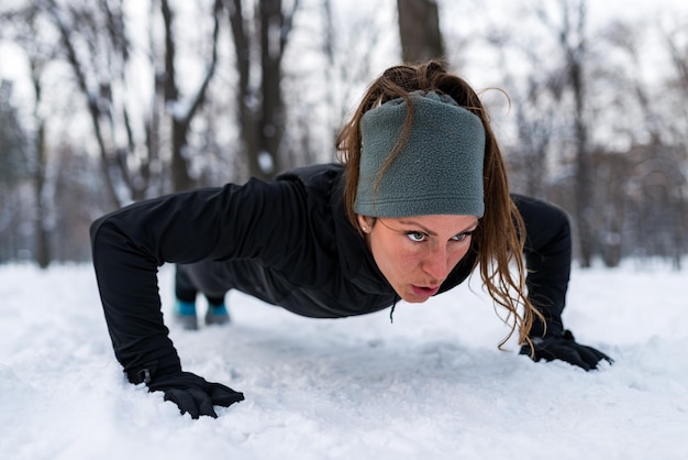 Female athlete exercising in park on winter day Listening music and exercising