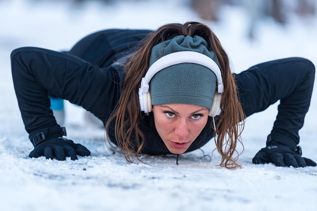 Female athlete exercising in park on winter day Listening music and exercising