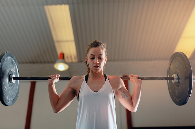 体育館でバーベルで運動する女子アスリート