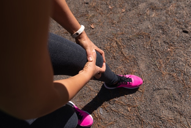 Female athlete holds hands on knee feeling pain