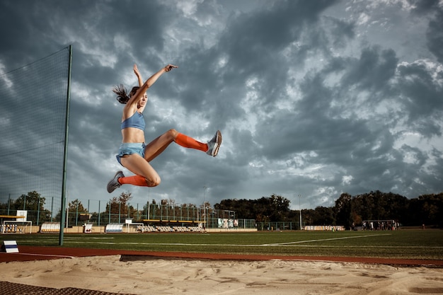경기장에서 훈련에서 점프 하는 여성 운동 선수. 점프, 운동 선수, 액션, 모션, 스포츠, 성공 및 훈련 개념