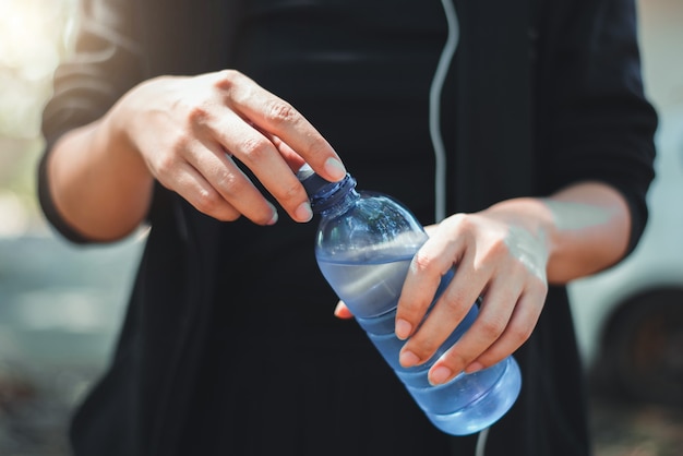 Female athlete opening the plastic cap of mineral water bottle