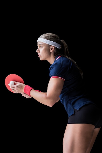 Female athlete playing ping pong on black