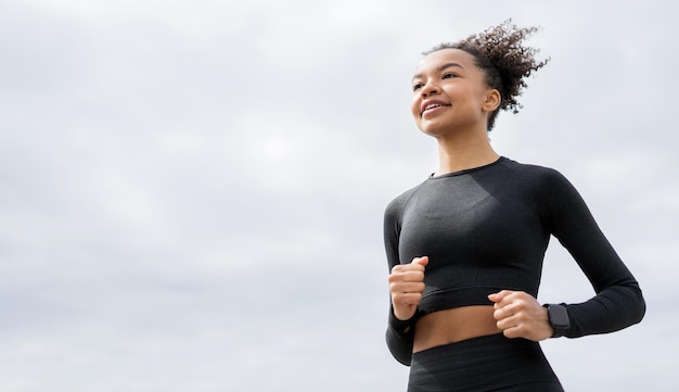 A female athlete runs does a workout on the street in sportswear and a fitness watch on her hand