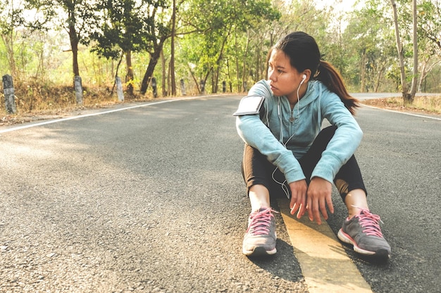 写真 森の道路に座っている女性アスリート