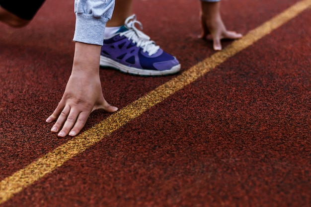 Atleta femminile sulla linea di partenza di una pista dello stadio preparando per una corsa