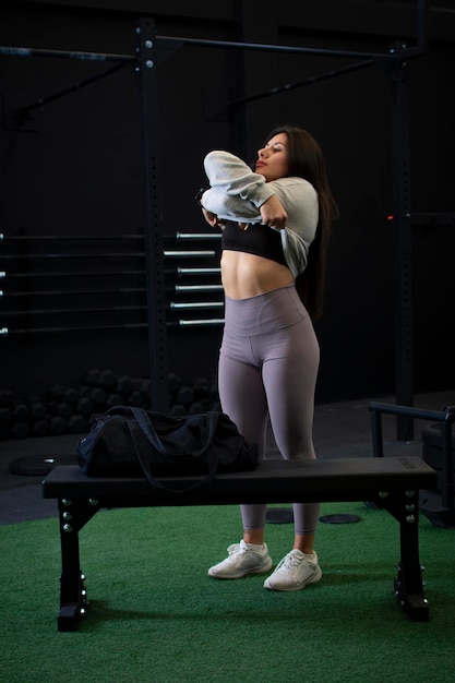 사진 체육관 에서 운동 을 하기 위해 스웨트 셔츠 를 벗고 있는 여자 운동 선수