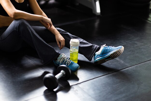 Female athlete taking rest after exercising at gym. Fitness Healthy lifestye and workout at gym concept.