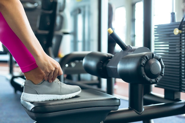 Photo female athlete tying her shoelaces in fitness studio