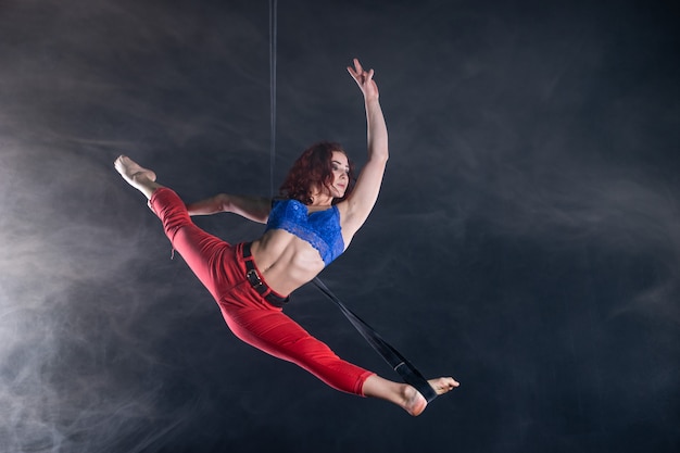 Female athletic, sexy and flexible aerial circus artist with redhead on aerial straps