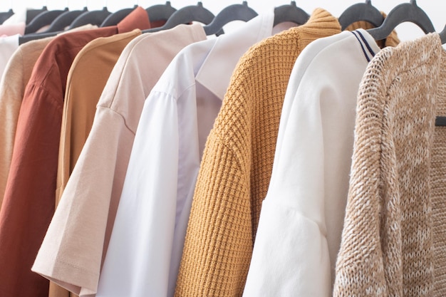 Female autumn clothes on hangers in white room