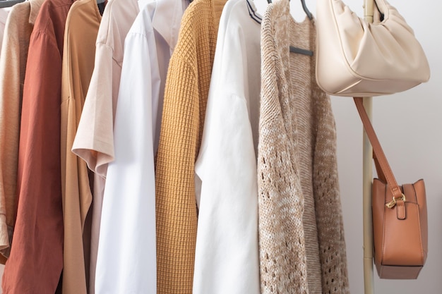 Female autumn clothes on hangers in white room