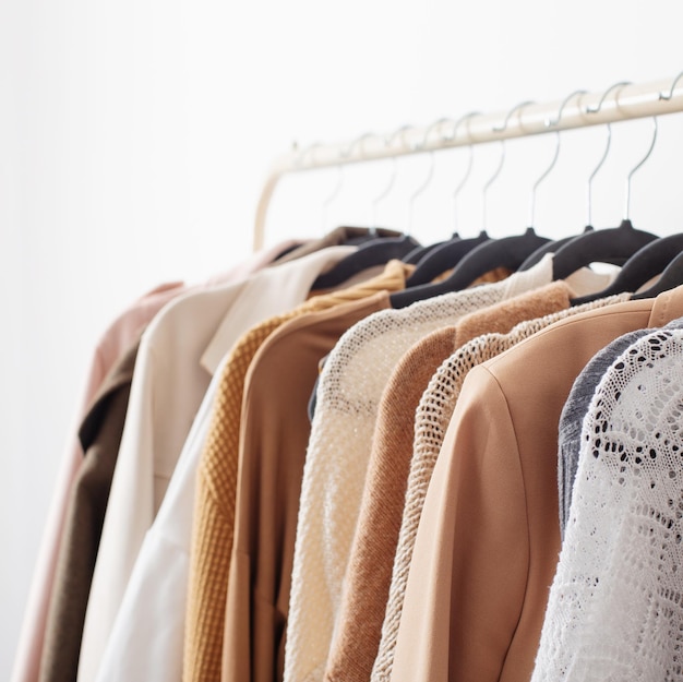 Female autumn clothes on hangers in white room