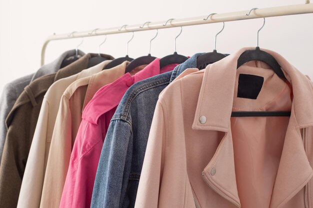 Female autumn clothes on hangers in white room