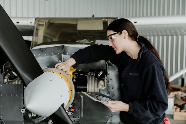 Tecnico dell'aviazione femminile che ripara il motore di un aereo a elica