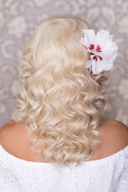 花の結婚式のヘアスタイルと長い巻き毛のブロンドの髪を持つ女性の背中
