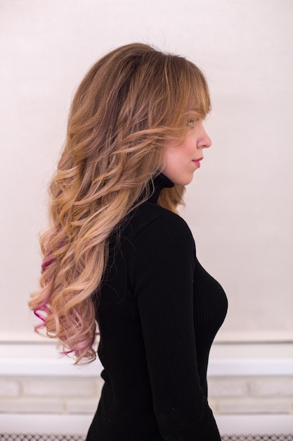 Female back with long, curly, brunette wedding hairstyle, in hairdressing salon