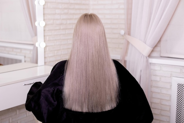 Female back with long straight blonde hair in hairdressing salon