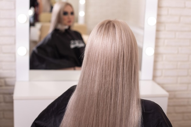 Female back with long, straight, blonde hair, in hairdressing salon