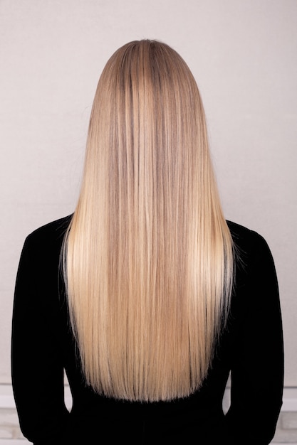 Female back with long straight blonde hair in hairdressing salon