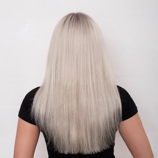 Female back with long straight healthy blonde hair on hairdressing salon background