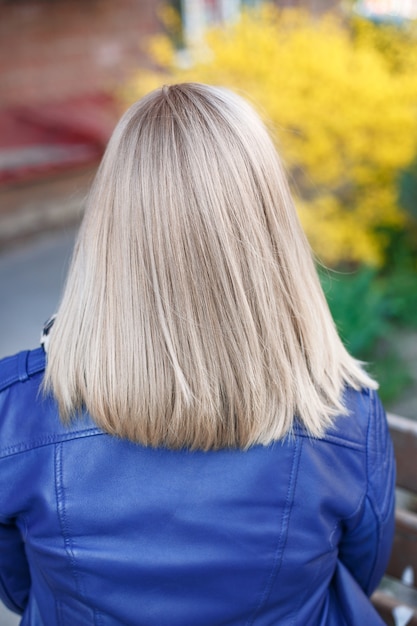 Dorso femminile con capelli biondi corti e lisci