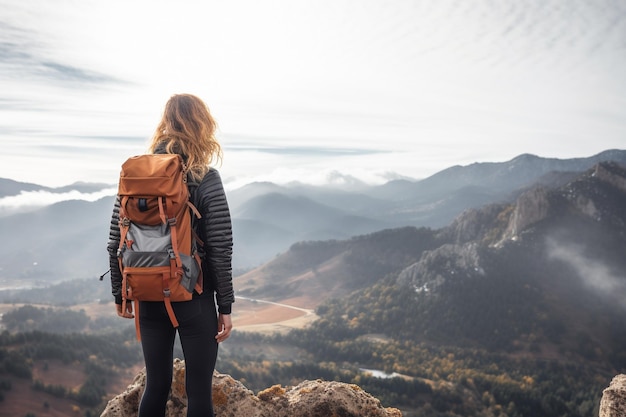 Female backpacker enjoying the view on the edge of a mountain peak cliff