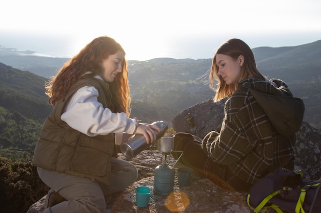 Female backpackers boiling tea water on camp stove outdoors