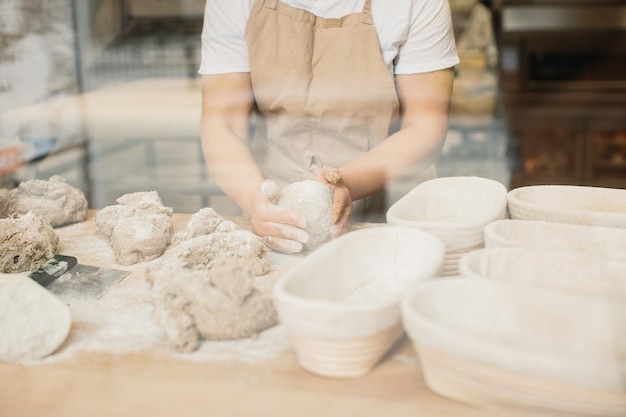 Женщина-пекарь замешивает тесто в пекарне