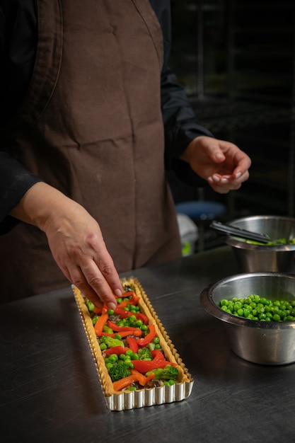 女性のパン屋は野菜のパイを準備します