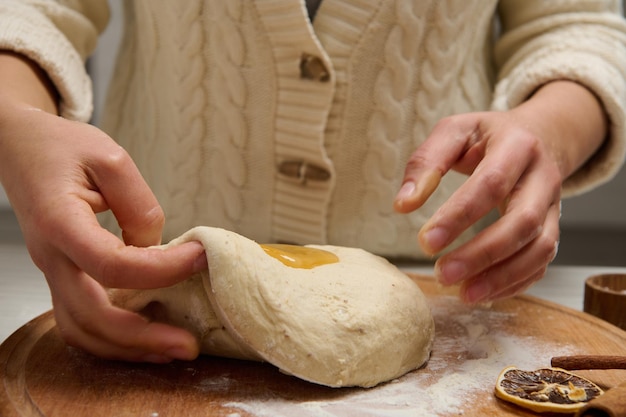 Fornaio femminile che prepara pan di zenzero, pasta di pane, impastando la pasta su una tavola di legno in cucina