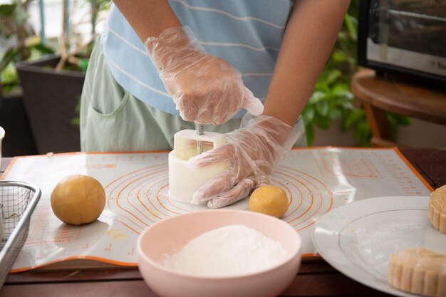 Photo female baker pressing raw dough bun with mold to make beautiful mooncake mooncake making process