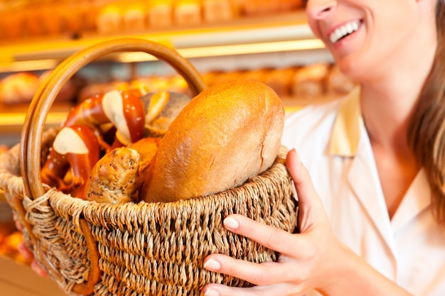 Female baker selling bread by basket in bakery