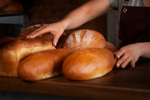 Foto panettiere femminile con pane cotto in pasticceria