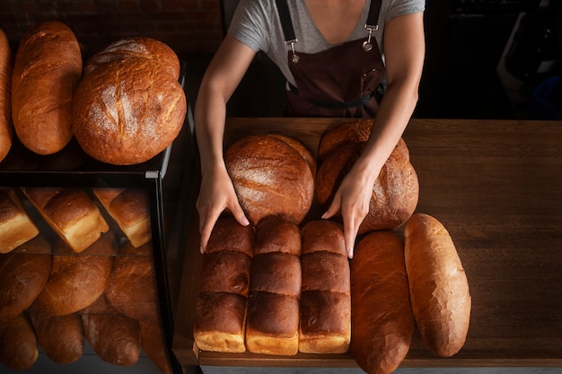 Foto panettiere femminile con pane cotto in pasticceria