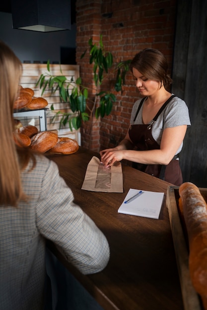 Foto panettiere femminile con il cliente al negozio di panetteria