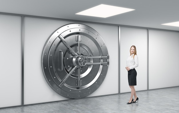 Photo female bank worker standing in front of a big locked round metal safe in a bank depository a concept of security and client service