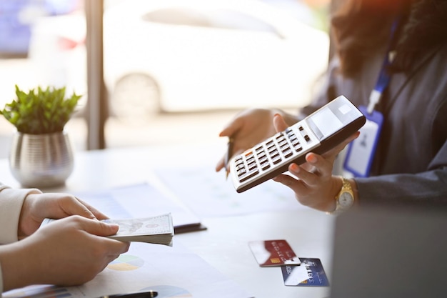 Female banker showing the profit margin on calculator to a customer side view