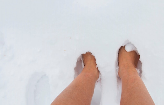 Female bare feet on a winter frosty day in a snowdrift of snow, hardening of the body