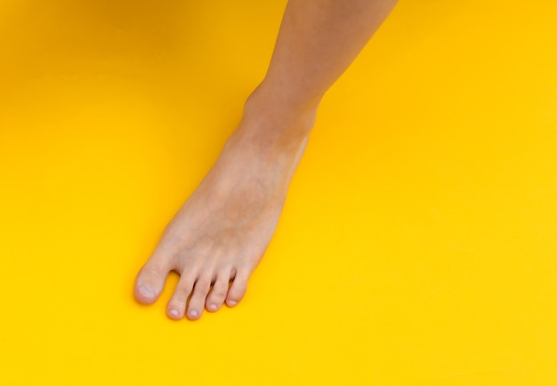 노란색 배경에 여성 맨발입니다. 뷰티 케어 개념