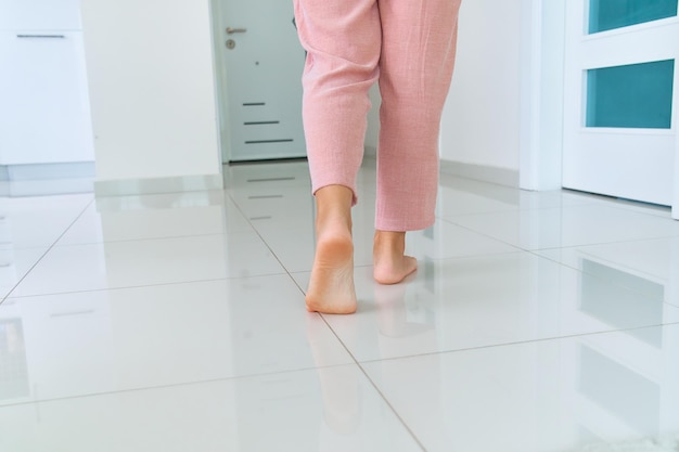 Female barefoot legs on heated warm floor in living room at home