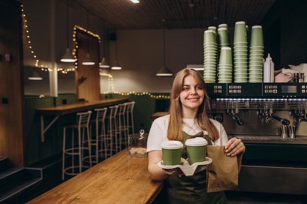 Female barista giving coffee in cardboard cups