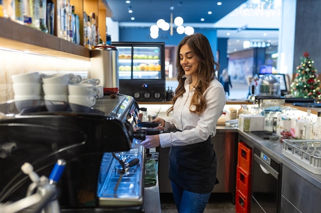 Foto barista femmina che fa il caffè nel bancone di una caffetteria barista bella che fa l'espresso su una macchina da caffè professionale in un caffè